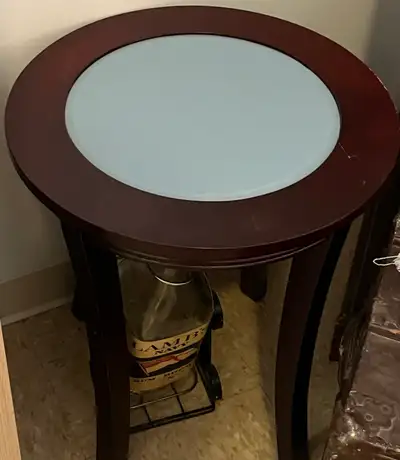 High-end side table. Either mahogany or dark walnut with a light blue glass top. It's a round table...