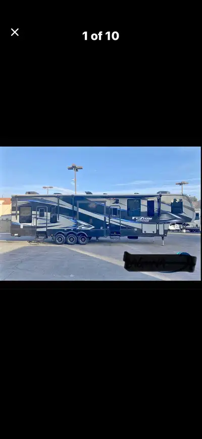 Spacious 2015 Fuzion Chrome 5th wheel toy hauler has triple axle setup and multiple slide-outs for e...