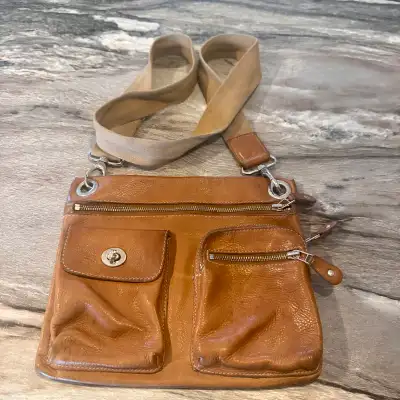 This is a pre-owned Roots crossbody bag, perfect for everyday use. It features a tan leather exterio...