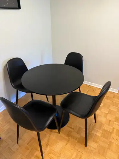 Upgrade your home with this sleek black dining set featuring a round table and four matching chairs,...