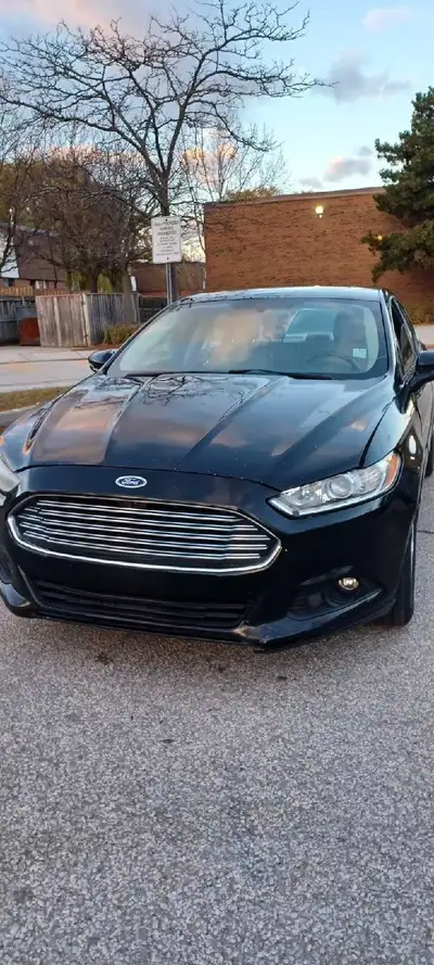 This Ford Fusion is a reliable sedan featuring a sleek black exterior and a comfortable beige interi...