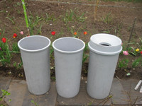 Three  tall, round, grey, plastic bins/ barrels/planters!