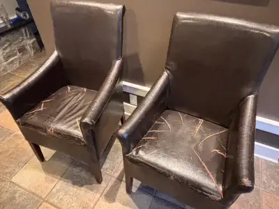 Pair of bonded leather armchairs with wooden legs. Some cracking in seats but the rest is in good sh...