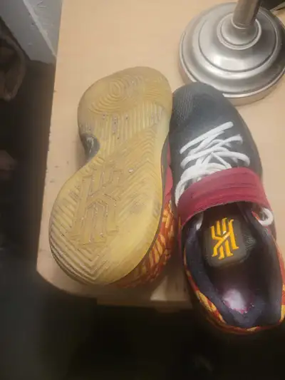 Nike Kyrie basketball shoes in a size 9.5. These sneakers feature a black toe box with a red and yel...