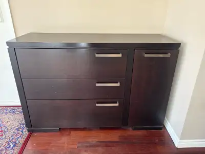 This used dresser features three drawers and a side cabinet, providing ample storage space. While it...