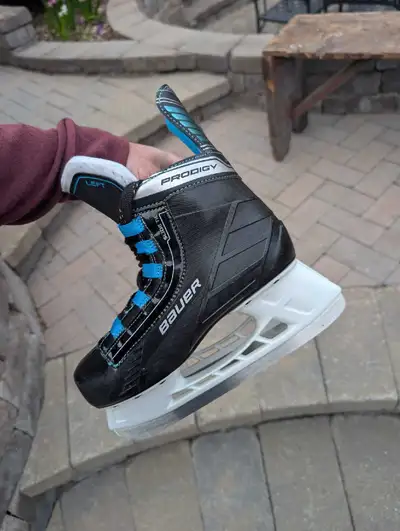 These Bauer Prodigy ice skates are black with blue accents. They have a padded collar and tongue for...