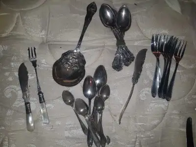 Elegant silver-toned flatware set includes a variety of spoons, forks, and knives. The collection ha...