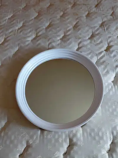 A simple white round wall mirror. It has a ribbed frame. Ready to hang on your wall!