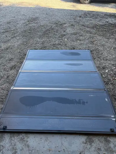 This used black Tonneau Cover is designed for GMC HD trucks. It's a hard top cover that folds in sec...