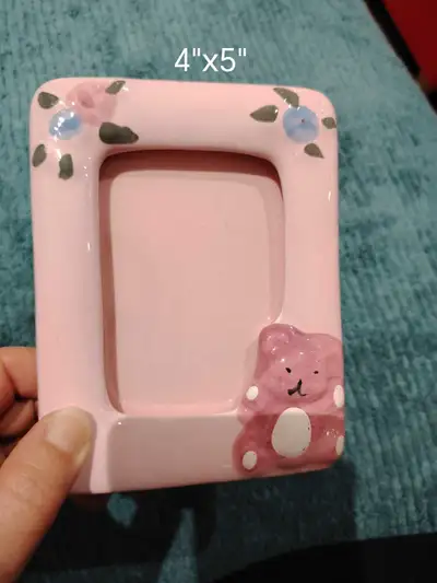 This is a charming, pink ceramic picture frame with a teddy bear and floral design, perfect for disp...
