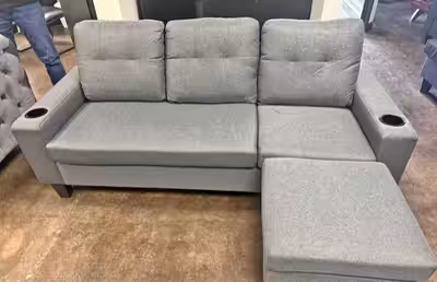 This is a used grey sectional sofa with a pull out storage ottoman, perfect for adding extra seating...