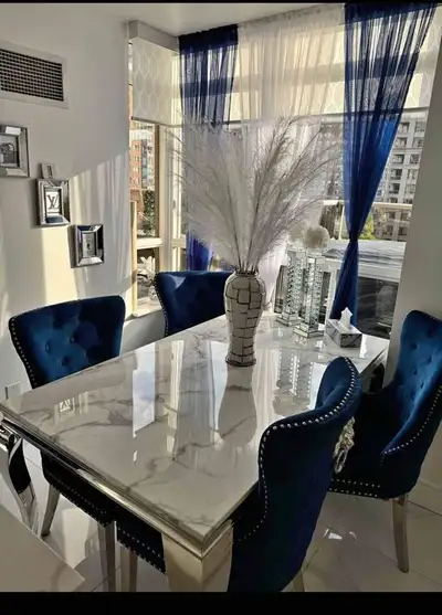 A luxurious 6‑seater dining set featuring a glossy marble‑style table paired with six navy velvet ch...