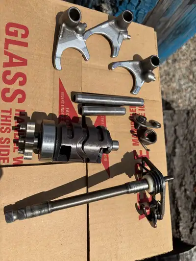 Transmission shifter components of a 1984 Yamaha IT490. This set includes three shift forks, a shift...