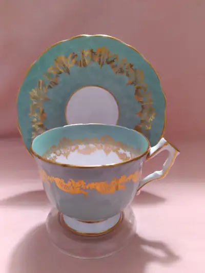 A nice, vintage rare Aynsley cup and saucer, in blue with gold lace around the cup and saucer. It is...