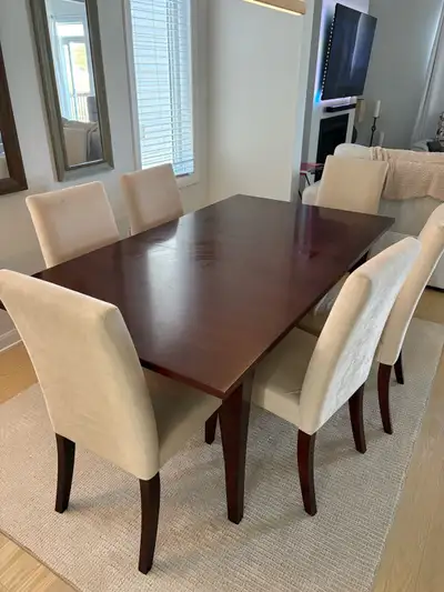 This dining room set features a table with a rich, dark wood finish and includes six upholstered cha...