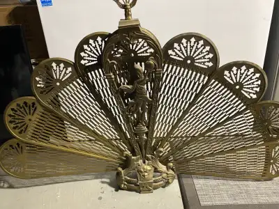 This is a used brass fireplace screen that features an ornate, vintage design with a central figure....
