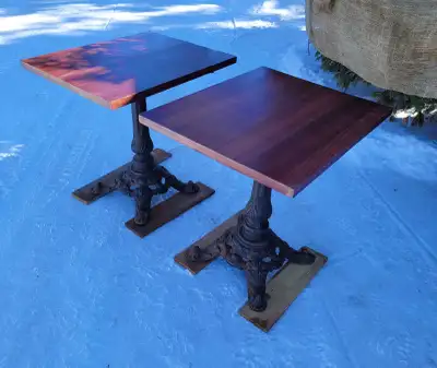 Cast iron pedestal bistro tables with butchers block tops. Tops have some minor wear but could be re...