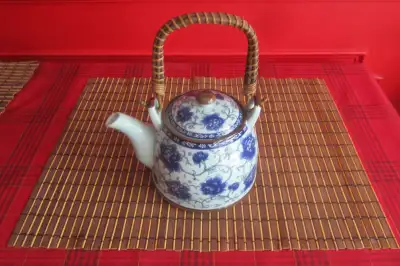 This pretty teapot has a built in infuser and a wicker handle. It is pale blue with a dark blue peon...