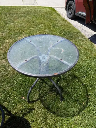 This circular glass-topped patio side table features a sturdy metal frame and is perfect for holding...