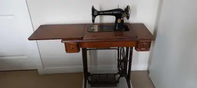 This vintage Singer treadle sewing machine is a well-loved piece featuring a classic cast-iron base...