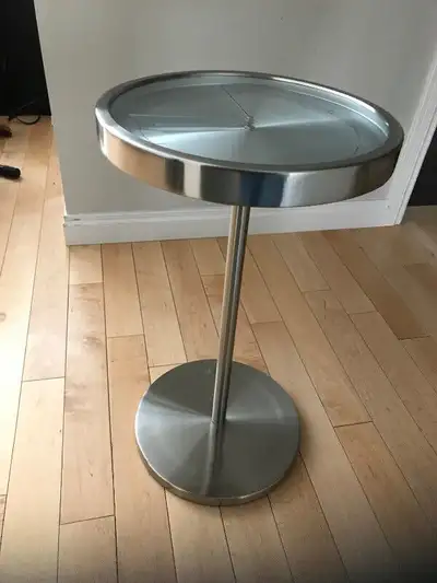 Umbra Clock Table Glass top and metal stand . Very sturdy . Great for beside sofa , chair. Or by bed...