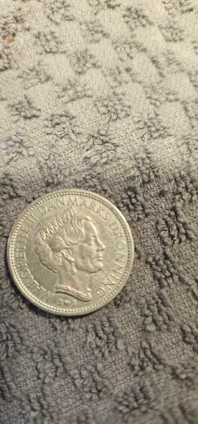 This 1979 Denmark 10 Kroner coin features the profile of Queen Margrethe II on the obverse and is in...
