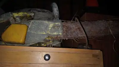 Vintage chainsaw with a 20-inch bar, showing its age with visible wear and rust. This item is in use...