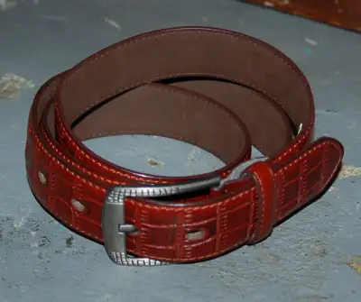 $10 Tooled leather belt with gunmetal grey buckle. Overal length 54", notches from 46"-50"