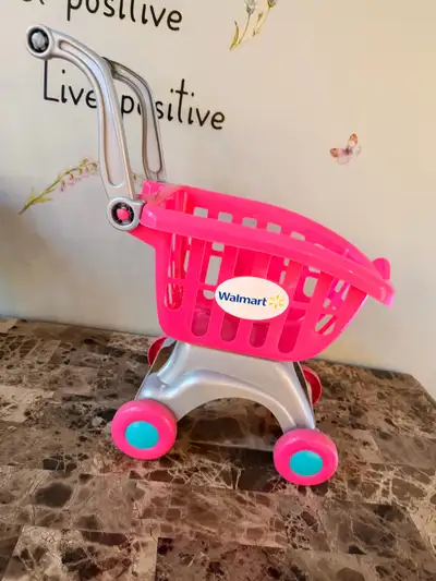 This is a pink Walmart shopping cart, perfect for your little one's imaginative play! It's in good c...