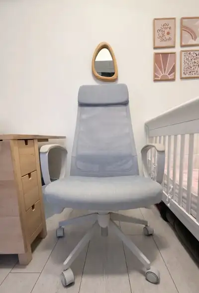 A comfortable grey office chair featuring a mesh back and a padded headrest. It has adjustable armre...