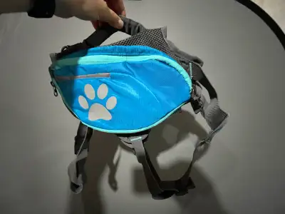 This is a blue dog backpack that is in excellent used condition. It features a cute paw print design...