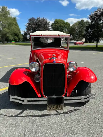 This is a classic Ford Model A Pheaton hot rod that boasts a stunning red exterior paired with a whi...