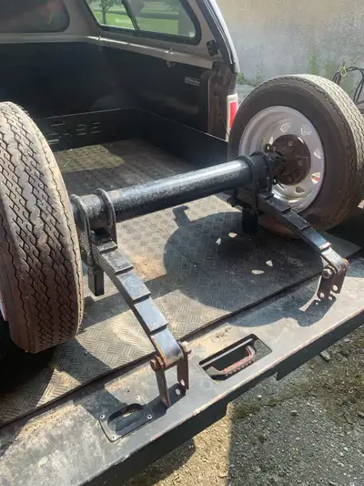Here is a trailer axle with leaf springs and tires. It has a 5 on 4.5 bolt pattern. Axle measures 37...