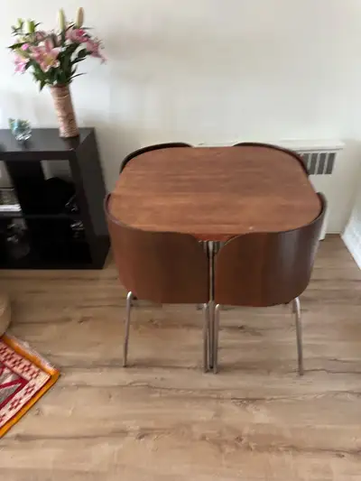 This stylish mid-century modern dining set includes a walnut veneer table and four matching chairs,...