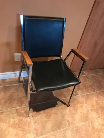 Chaise de bureau avec un cadre en métal et une assise et un dossier en similicuir noir classiques. L...