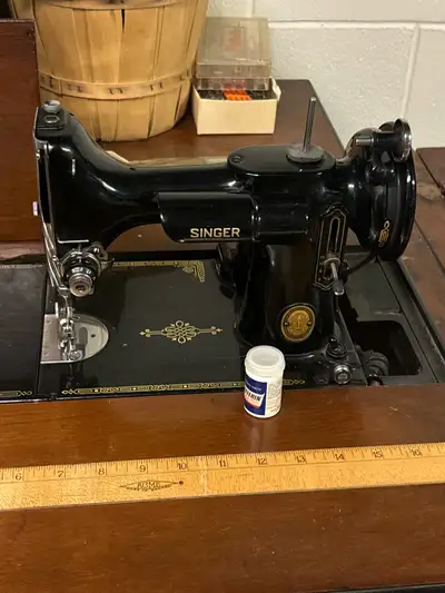 This is an antique Singer 201-2 sewing machine, complete with its original cabinet, offering a piece...