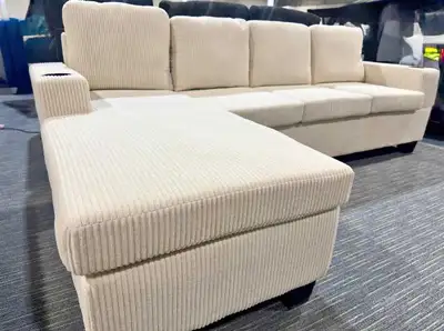 This cream corduroy sectional sofa features a spacious chaise lounge and convenient built-in cup hol...