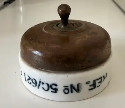 White Vitrious enamelled porcelain ceramic base with brass domed cover and toggle switch. Thought to...