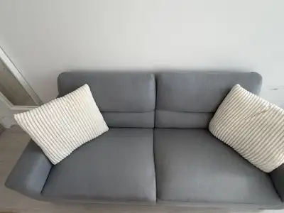 Grey sofa with 2 white accent pillows, View more