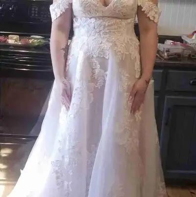 This stunning off-the-shoulder lace wedding dress features intricate floral applique details and a f...