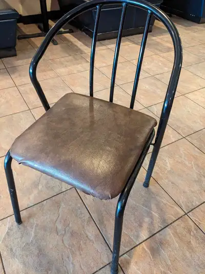 These restaurant chairs feature a durable black metal frame and a brown vinyl seat, perfect for comm...