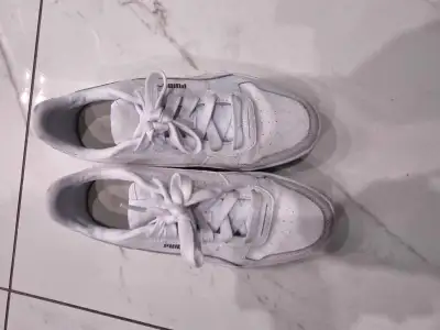 These white Puma sneakers feature a classic platform design with gold branding, perfect for adding a...