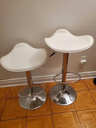 2 white barstools with footrest and adjustable height.
