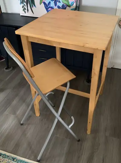 Selling a like-new wooden IKEA Bar Height Table and matching Chair (that folds down). There are hook...