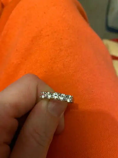 This elegant ring features a series of sparkling stones set in a sleek, white metal band. While it's...