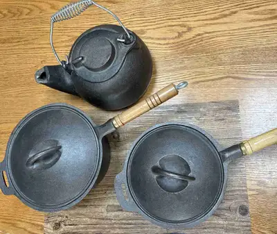 This is a brand new, never used vintage cast iron cookware set which includes a kettle and two woode...