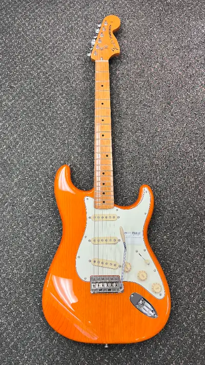 Fender Stratocaster made in Mexico with a glossy orange finish, three single-coil pickups, and a vin...