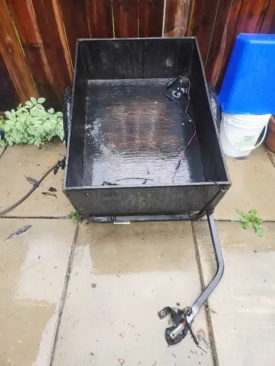 This is a bike cargo trailer with a wooden base and black wooden siding. It has seen some use, but s...