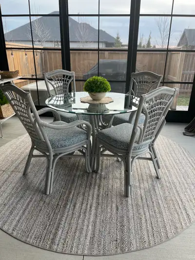 This used bamboo table set features a glass top and four chairs with comfortable, patterned cushions...