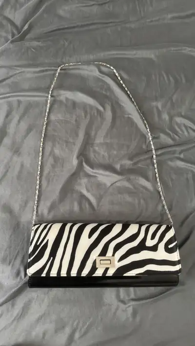 Add a touch of wild sophistication to your wardrobe with this chic zebra print clutch! This eye-catc...